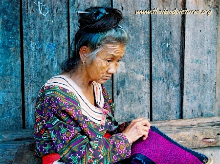 An old Thai woman sewing clothing.